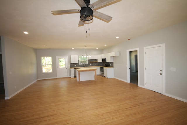 unfurnished living room featuring ceiling fan with notable chandelier, light hardwood / wood-style flooring, and sink