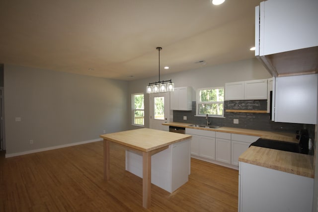 kitchen featuring light hardwood / wood-style floors, pendant lighting, sink, stainless steel dishwasher, and white cabinetry