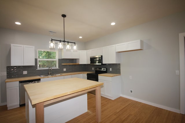 kitchen with hanging light fixtures, light hardwood / wood-style flooring, stainless steel appliances, and white cabinets