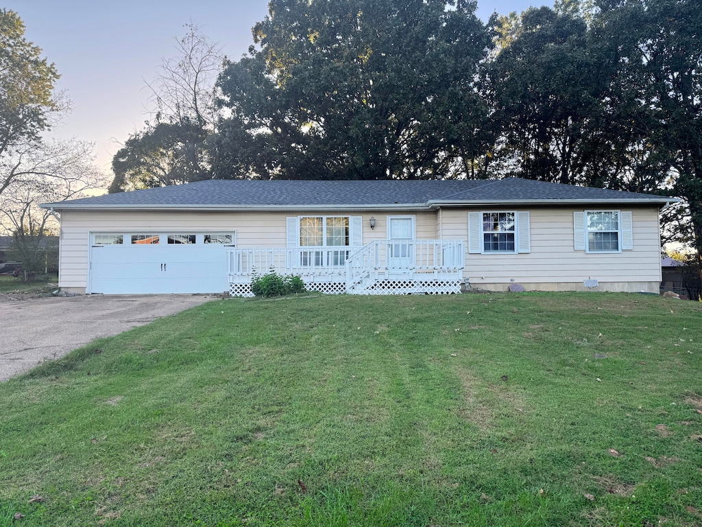 single story home featuring a lawn and a garage