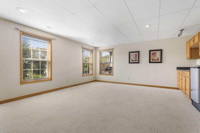 unfurnished living room featuring baseboards, recessed lighting, a paneled ceiling, and light colored carpet