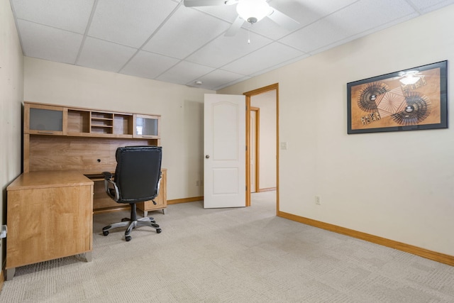 home office featuring a paneled ceiling, baseboards, a ceiling fan, and light colored carpet