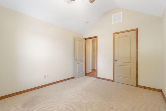 unfurnished bedroom featuring light carpet, visible vents, baseboards, vaulted ceiling, and a closet