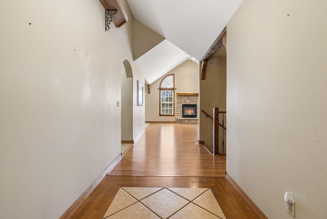 hall with light wood finished floors, baseboards, and arched walkways