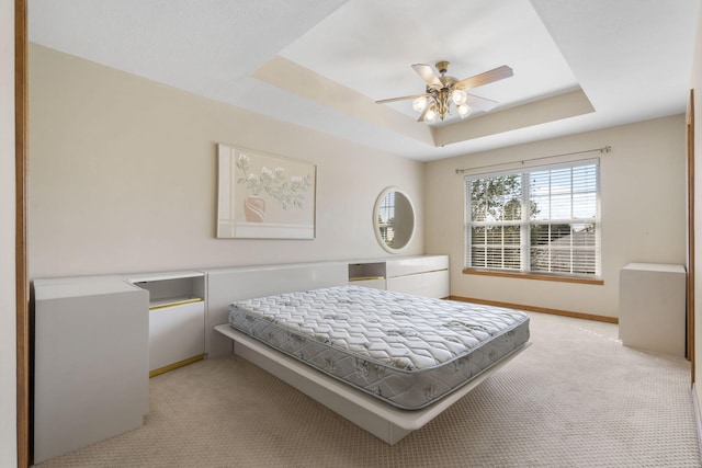 bedroom with light carpet, ceiling fan, a raised ceiling, and baseboards