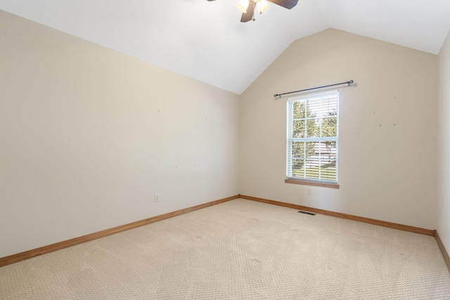 spare room featuring carpet, lofted ceiling, visible vents, a ceiling fan, and baseboards