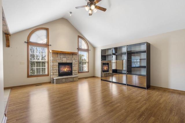 unfurnished living room featuring a fireplace, a ceiling fan, wood finished floors, high vaulted ceiling, and baseboards