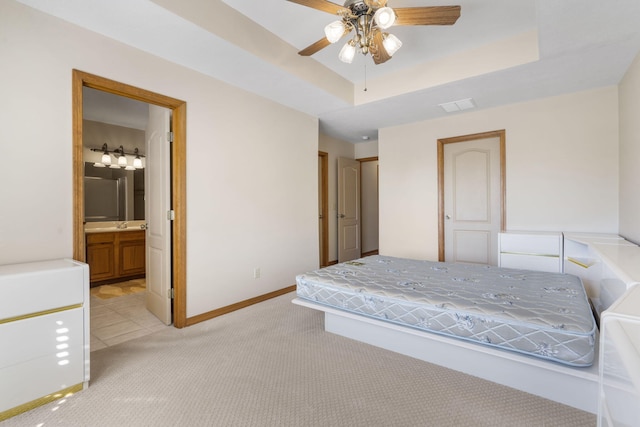 bedroom with light carpet, visible vents, a tray ceiling, and baseboards