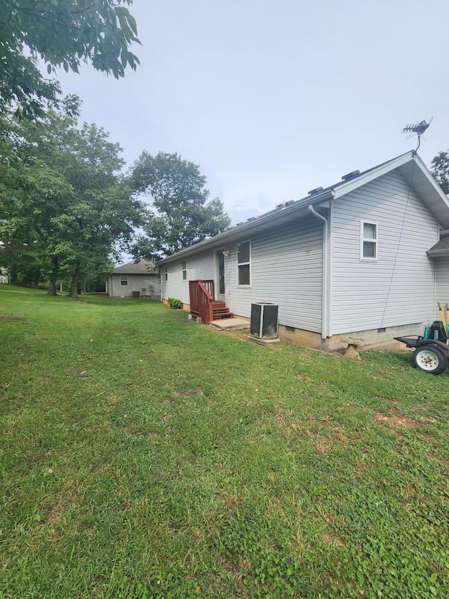 back of property with a yard and central AC