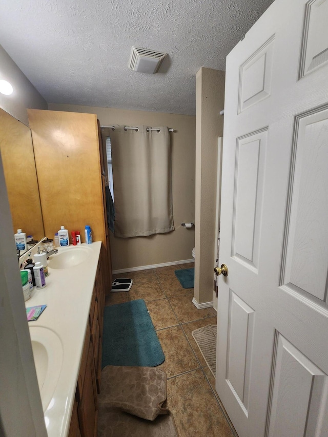 bathroom with tile patterned flooring, vanity, and a textured ceiling