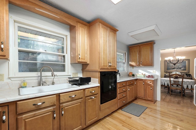 kitchen featuring oven, a notable chandelier, light hardwood / wood-style flooring, and sink