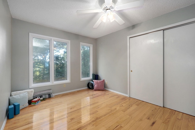 interior space with ceiling fan, a closet, light hardwood / wood-style floors, and a textured ceiling