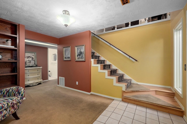 stairway featuring a wealth of natural light, carpet floors, and a textured ceiling