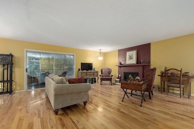 living room with a fireplace, light hardwood / wood-style floors, and a textured ceiling