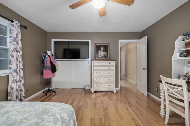 bedroom featuring light hardwood / wood-style flooring, a textured ceiling, and ceiling fan