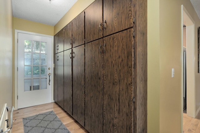 doorway featuring light hardwood / wood-style floors and a textured ceiling