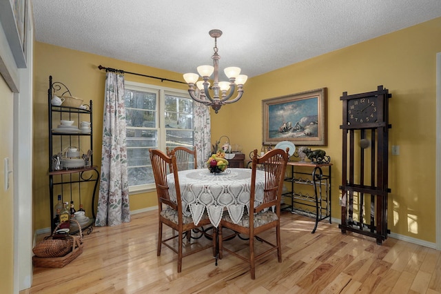 dining space featuring a textured ceiling, a chandelier, and light hardwood / wood-style floors