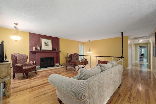 living room with a brick fireplace, hardwood / wood-style floors, and a textured ceiling