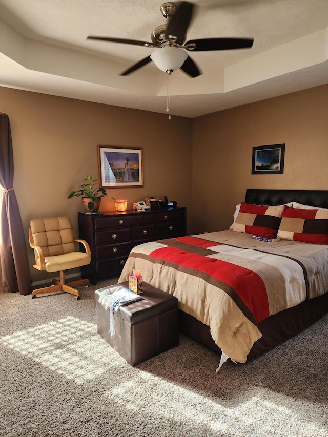 carpeted bedroom featuring ceiling fan and a raised ceiling