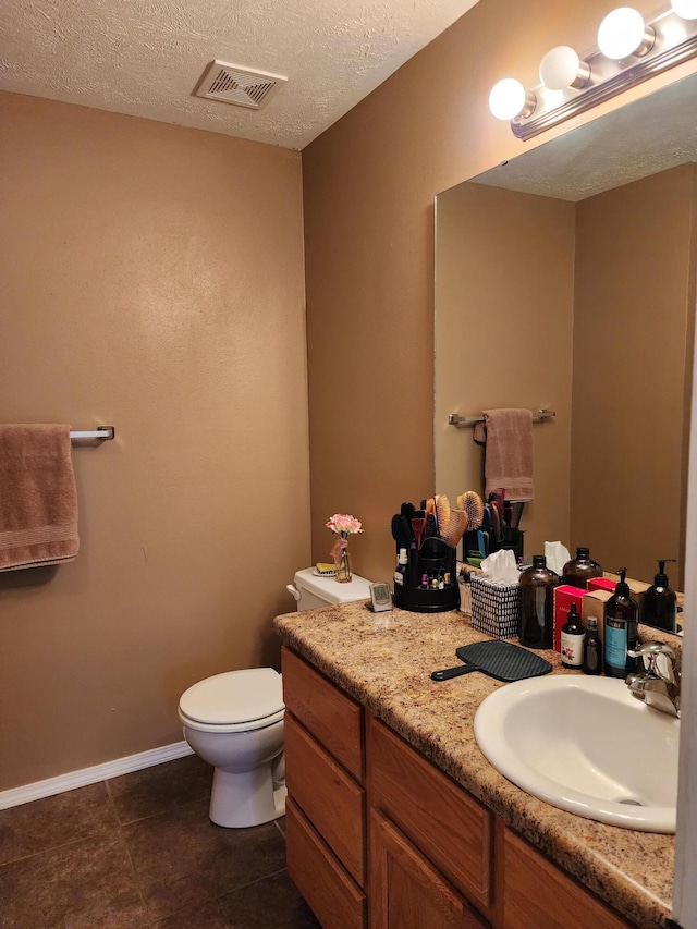 bathroom with a textured ceiling, tile patterned flooring, vanity, and toilet