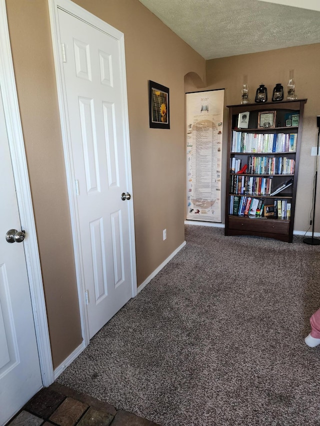 interior space with dark colored carpet and a textured ceiling