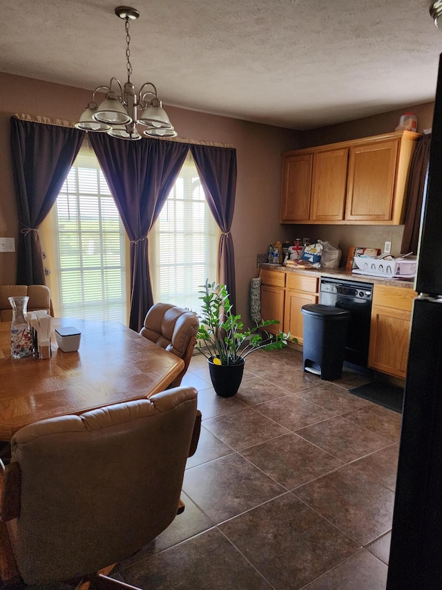 dining area featuring an inviting chandelier, dark tile patterned flooring, and a textured ceiling