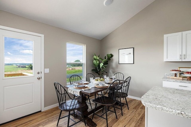 dining room with vaulted ceiling and light hardwood / wood-style floors