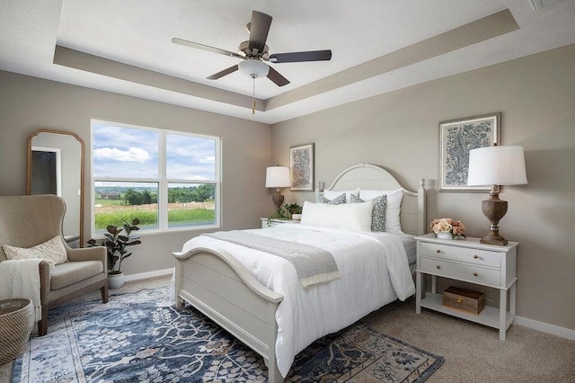 bedroom featuring carpet floors, a tray ceiling, and ceiling fan