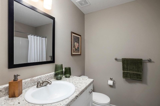 bathroom featuring vanity, toilet, curtained shower, and a textured ceiling