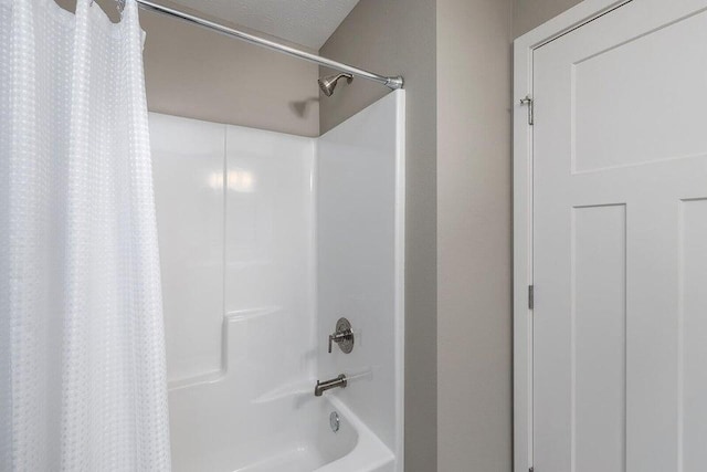 bathroom with a textured ceiling and shower / tub combo