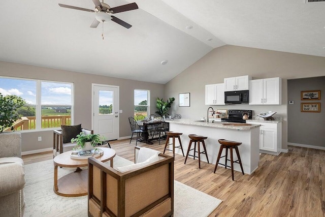 living room with light hardwood / wood-style floors, high vaulted ceiling, sink, and ceiling fan