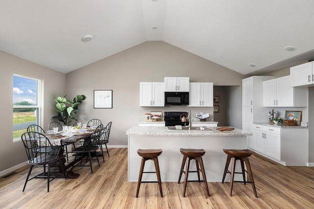 kitchen featuring white cabinets, light hardwood / wood-style flooring, vaulted ceiling, and black appliances