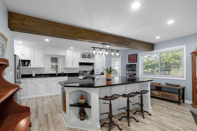 kitchen featuring a breakfast bar, appliances with stainless steel finishes, pendant lighting, beam ceiling, and white cabinets