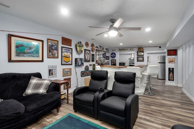 living room featuring hardwood / wood-style flooring, ceiling fan, and bar