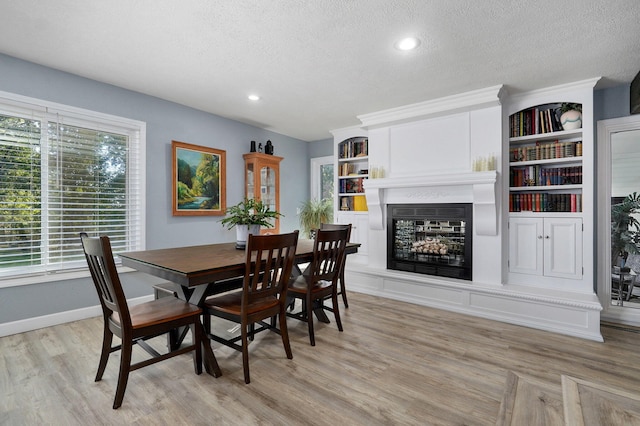 dining area featuring light hardwood / wood-style flooring, built in features, and a textured ceiling