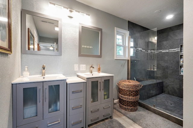 bathroom with hardwood / wood-style flooring, vanity, and tiled shower