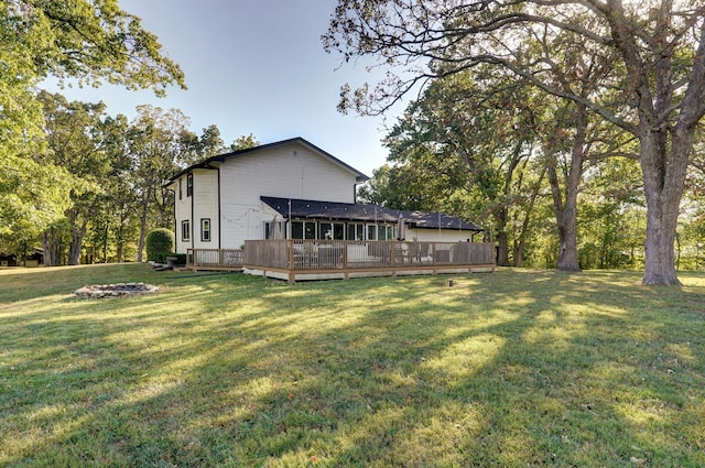 rear view of property featuring an outdoor fire pit, a deck, and a lawn