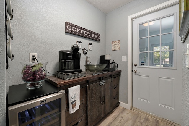 interior space with beverage cooler, sink, and light hardwood / wood-style flooring