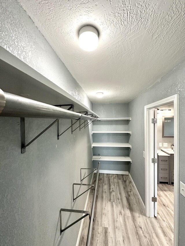 walk in closet featuring sink and light hardwood / wood-style floors