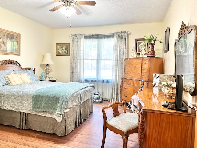 bedroom featuring light hardwood / wood-style floors, a textured ceiling, and ceiling fan