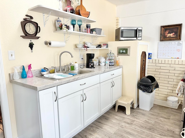 kitchen with white cabinets, sink, and light wood-type flooring