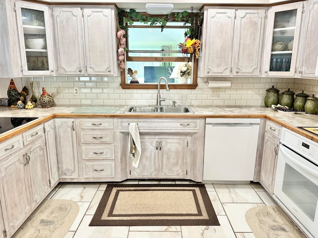 kitchen with decorative backsplash, white appliances, sink, and white cabinets