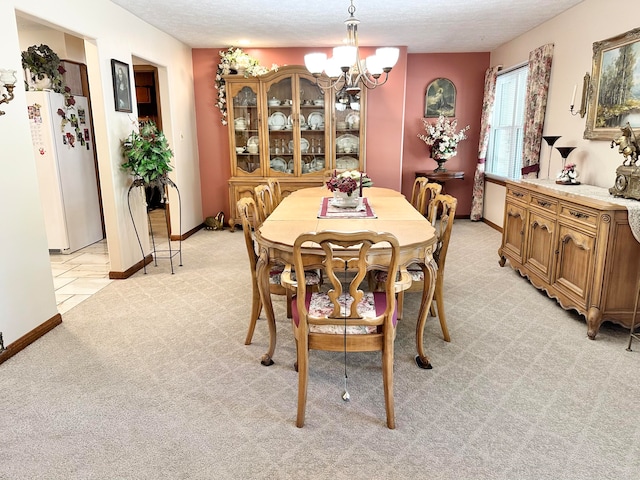 dining space with light colored carpet, a textured ceiling, and a chandelier