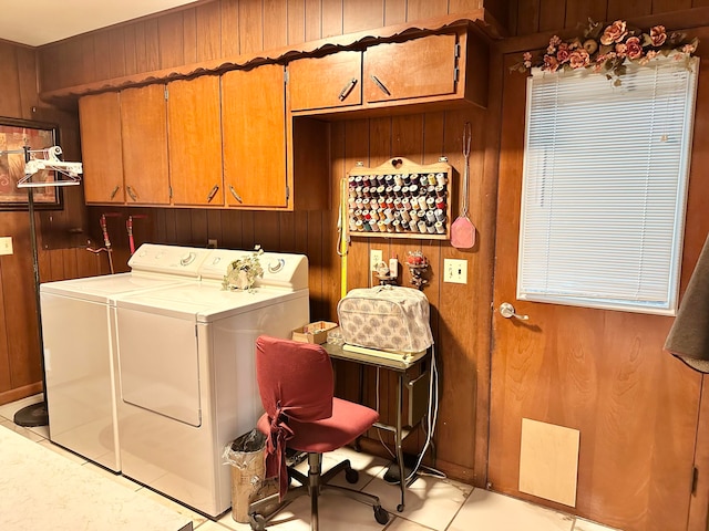 laundry area with cabinets, wood walls, light tile patterned floors, and independent washer and dryer