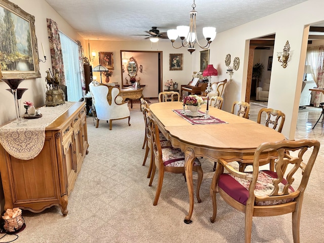 carpeted dining space with ceiling fan with notable chandelier and a textured ceiling