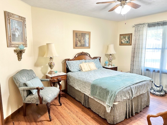 bedroom featuring light wood-type flooring, a textured ceiling, and ceiling fan