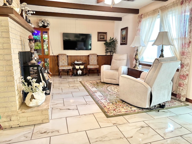 living room with wood walls, ceiling fan, and beam ceiling