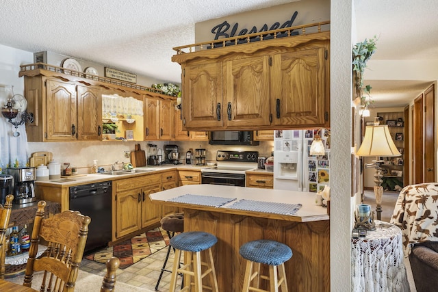 kitchen featuring black appliances, sink, kitchen peninsula, a kitchen breakfast bar, and a textured ceiling