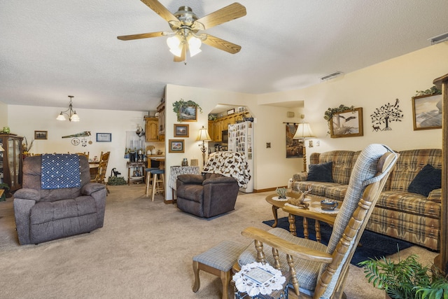 living room featuring ceiling fan with notable chandelier, a textured ceiling, and light colored carpet