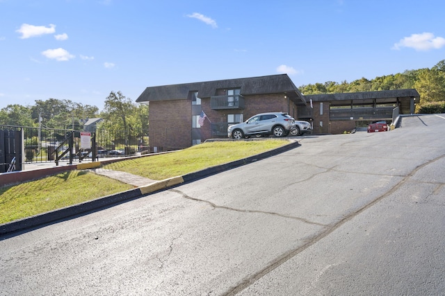 view of front of property with brick siding, a front lawn, and uncovered parking